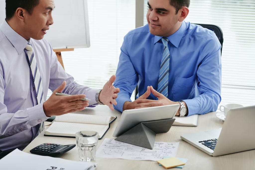 Two men engaged in conversation while dressed in corporate attire.